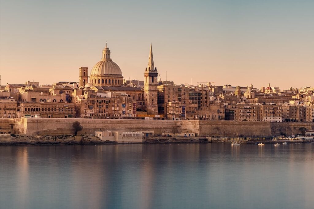 Golden-hour view of valletta skyline with st. paul's cathedral dome and waterfront.