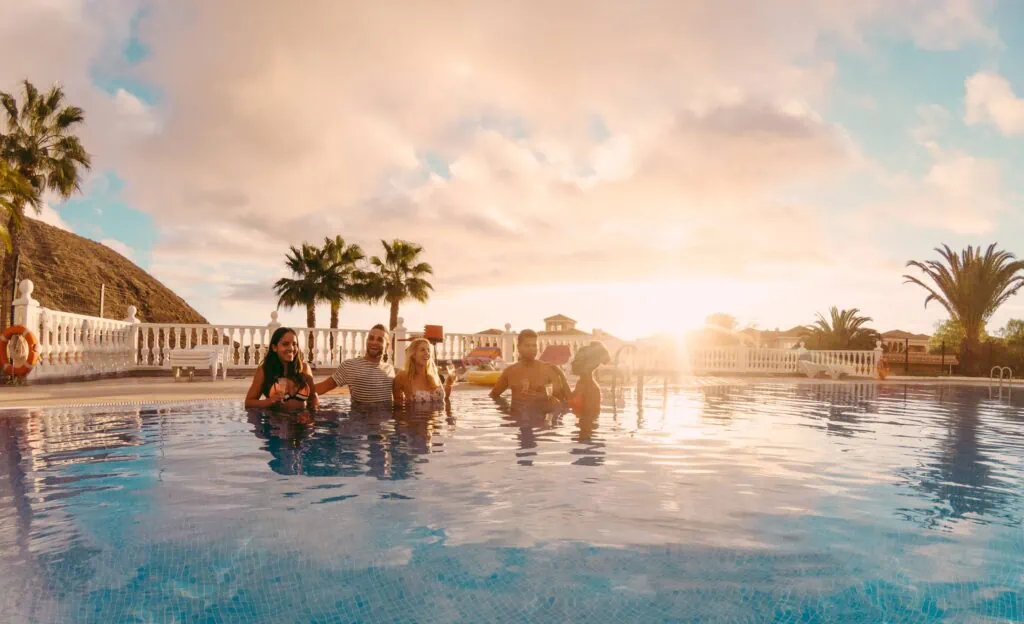 Group of friends enjoying a pool at sunset.
