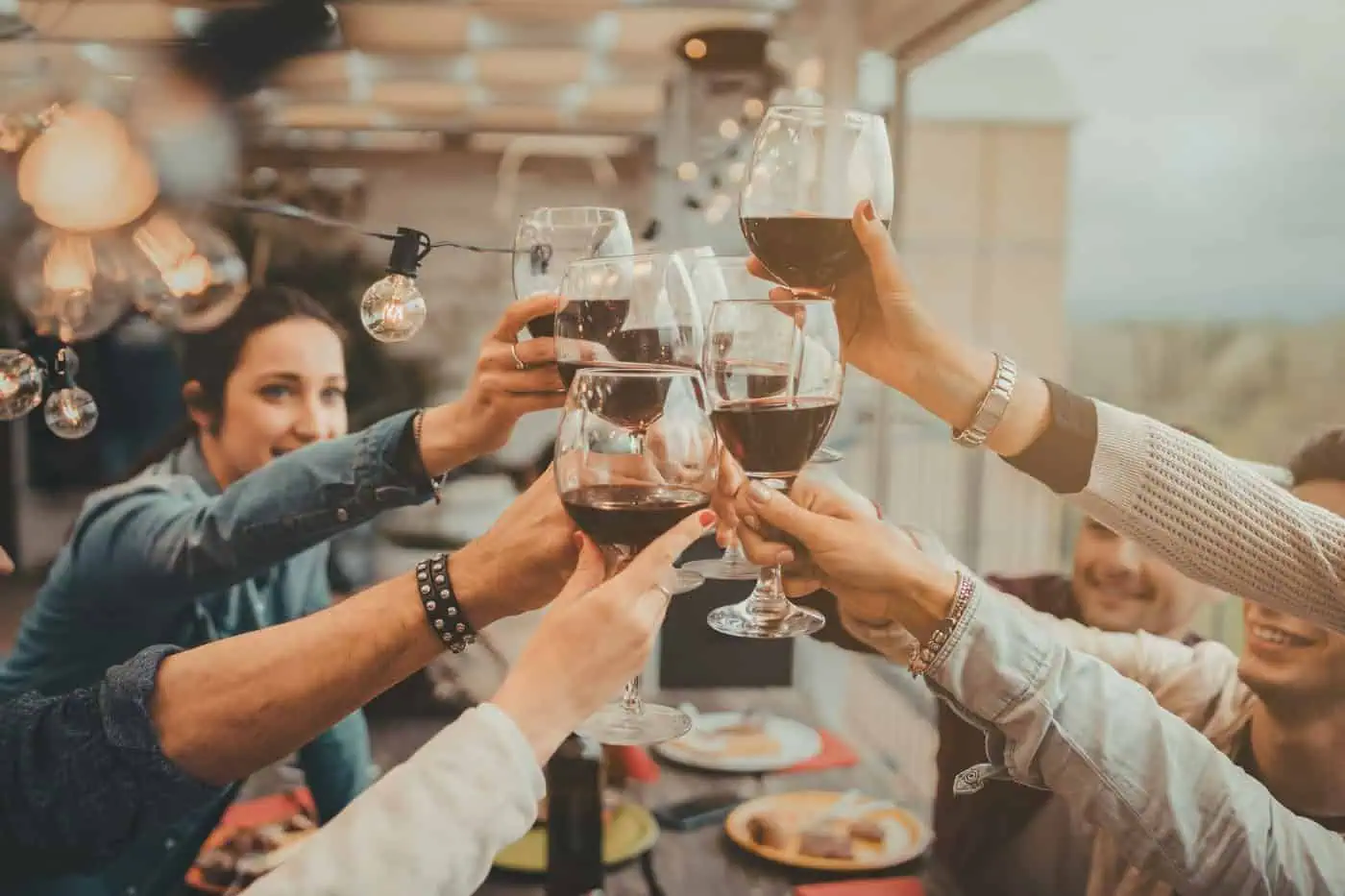 A group of people clink wine glasses together in a celebratory toast at a gathering indoors.