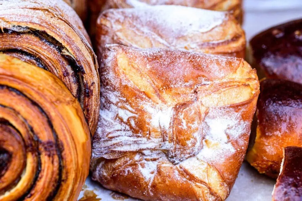 Close-up of a selection of freshly baked pastries, including a cinnamon roll and sugar-dusted turnover.