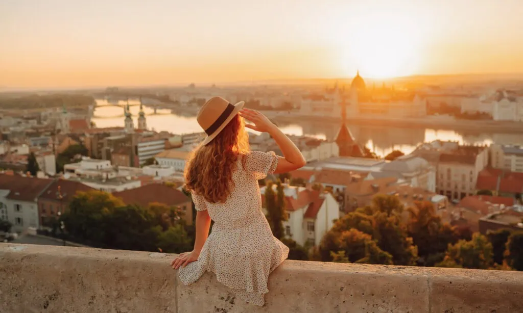 Young female tourist enjoys the view of the city at sunset. back view. Lifestyle, travel, tourism, nature, active life.