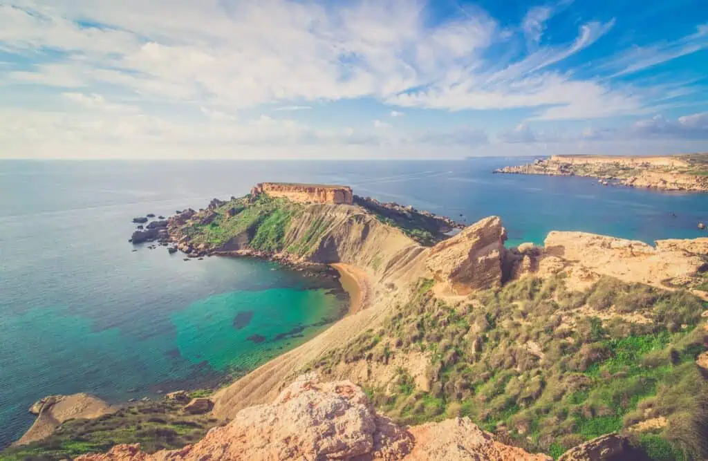 Eine Küstenlandschaft mit einer felsigen Halbinsel, die in ein ruhiges blaues Meer mit klarem Himmel darüber ragt.