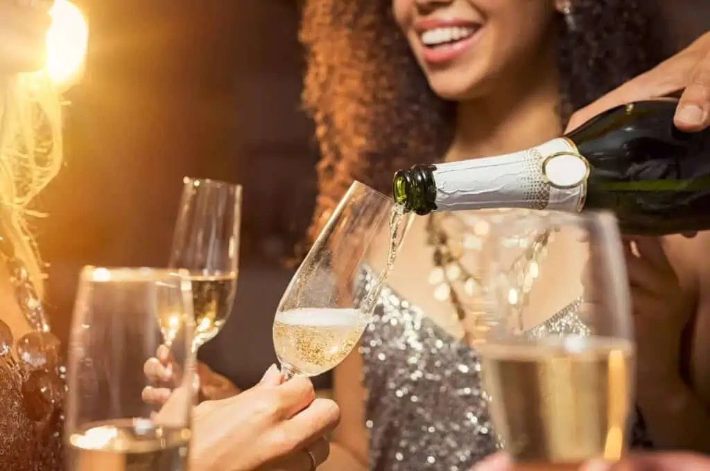 A group of people pours champagne into flutes at a celebration.